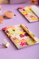 Spring Sweets Pocket Notebook A6 DUO - Lifestyle view on a purple background with a gold pen.