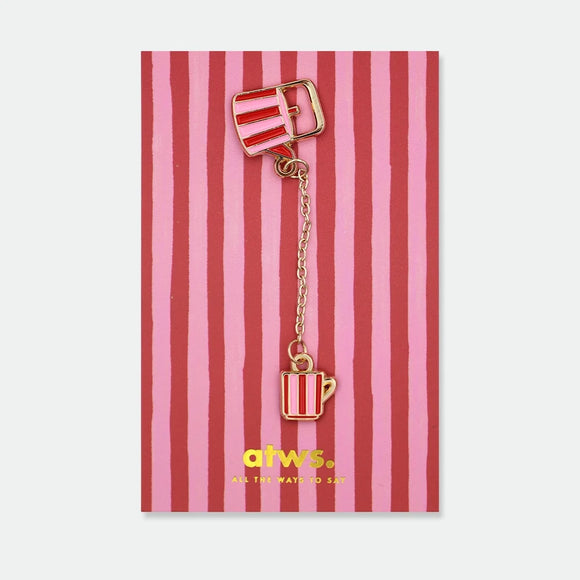 Enamel pin of a red and pink striped teapot connected by a gold chain to a matching striped teacup