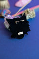 Back view of the tiger brooch showing the black velvet finish, secure gold safety pin clasp, and designer brand metal tag.