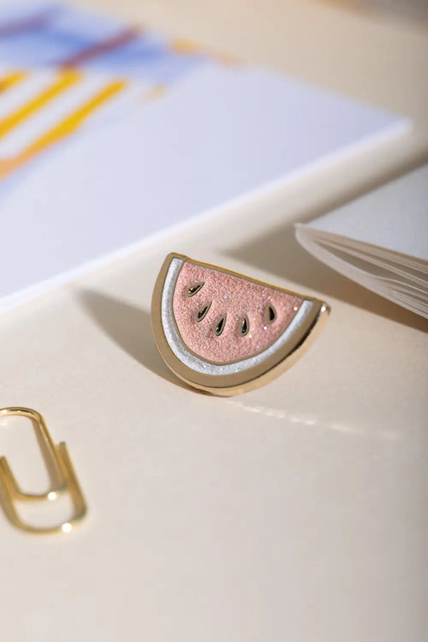 Watermelon - Pins: macro shot of the pink glitter texture and black seeds on the watermelon slice pin.