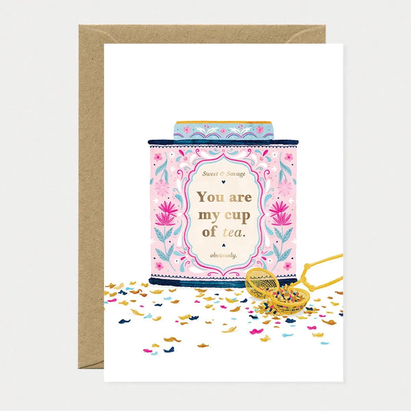 Illustrated greeting card of a pink and gold floral tea tin with a gold foil label reading "Sweet & Savage, You are my cup of tea, obviously," surrounded by loose tea leaves and confetti